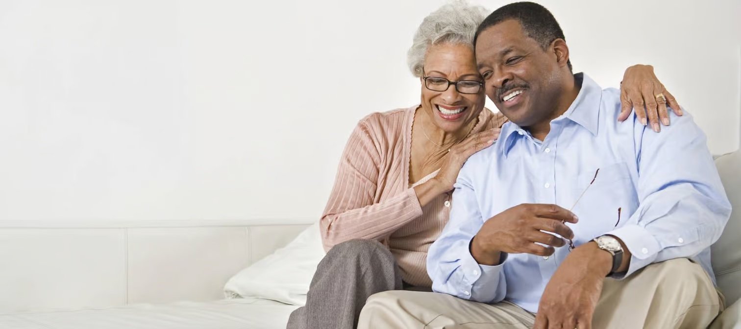 Older couple smiling and sitting on couch